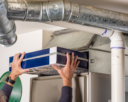 A repair technician installing a new furnace filter