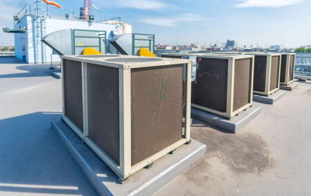 A row of commercial HVAC units sitting on the rooftop of a building