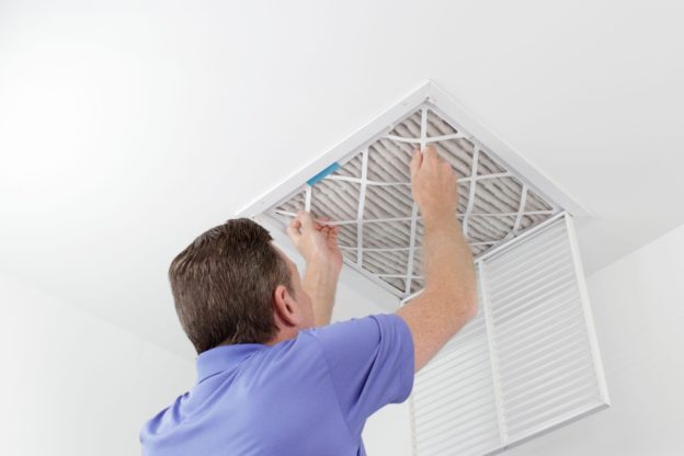 A man changing a ductwork vent filter
